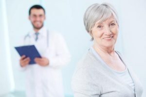 Senior patient looking at camera with doctor on background